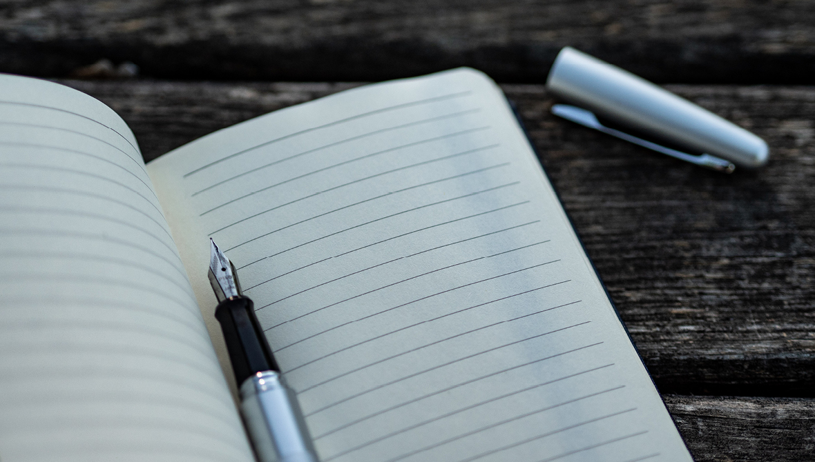 Photo of an open journal and pen on a wooden table