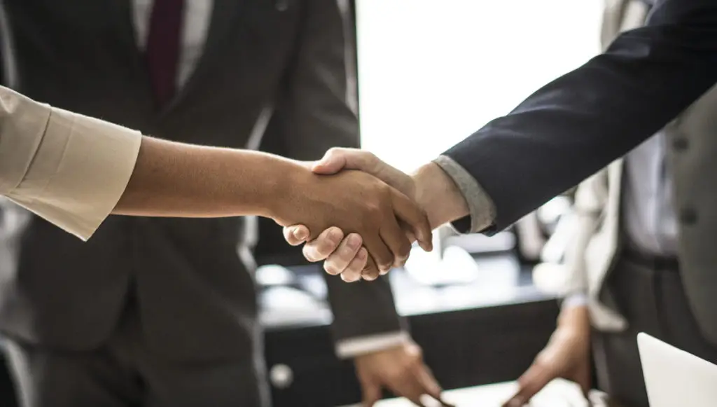Close-up photo of a businesswoman shaking hands with a businessman, symbolizing partnerships