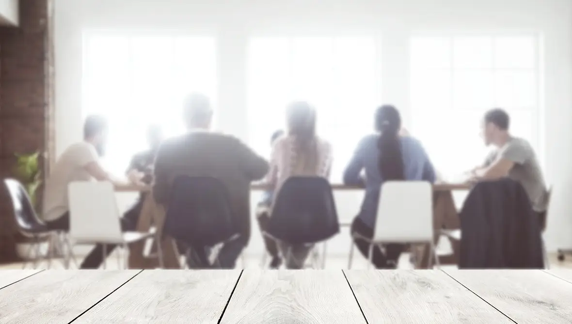 Photo of a group of professionals sitting around a conference table, representing meeting fcilitation
