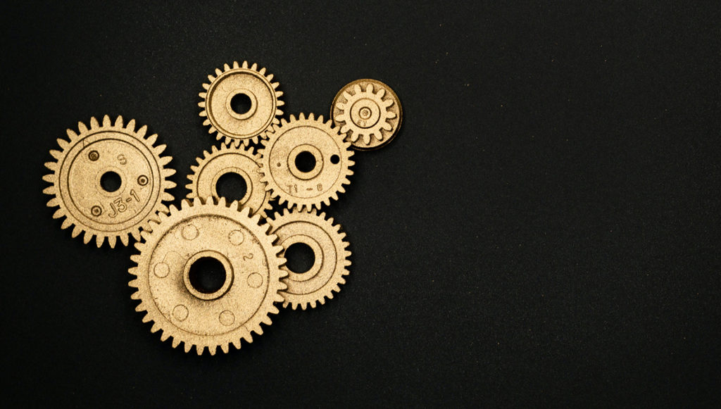 Photo of several brass interlocking gears on a black background
