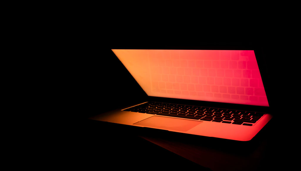 Photo of an open laptop in a dark room, symbolizing data and information
