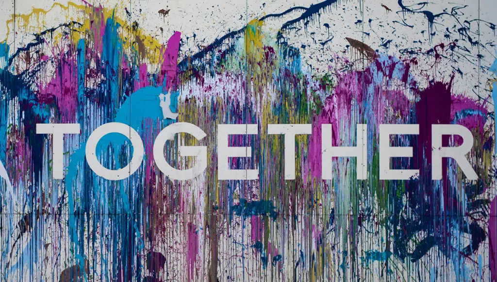 Photo of a wall splattered with paint and the word "TOGETHER" showing through the paint