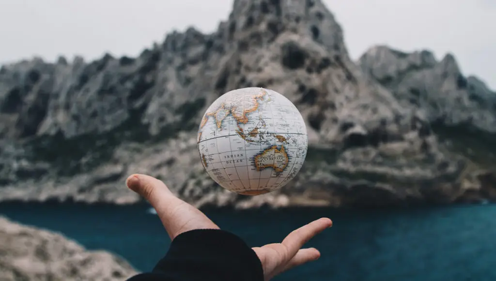 Photo of a person's hand holding a small globe