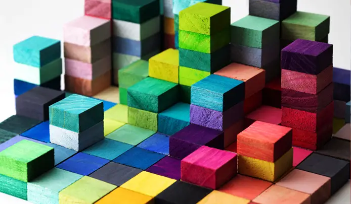 Photo of stacked building blocks of varying colors, symbolizing diverse strategies for prosperity