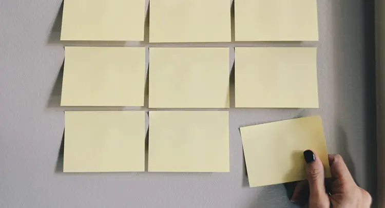 Photo of nine blank yellow sticky notes in a grid pattern on a wall
