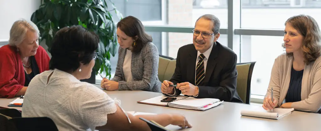 Photo: Members of the Johnson Center's leadership team seated at a conference table, engaged in discussion
