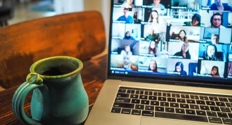 Photo of an open laptop on a table next to a cup of coffee