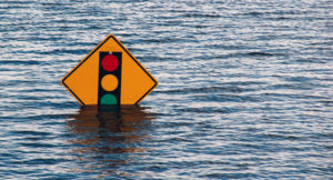 Photo of a traffic sign partly submerged in water in a flooded area