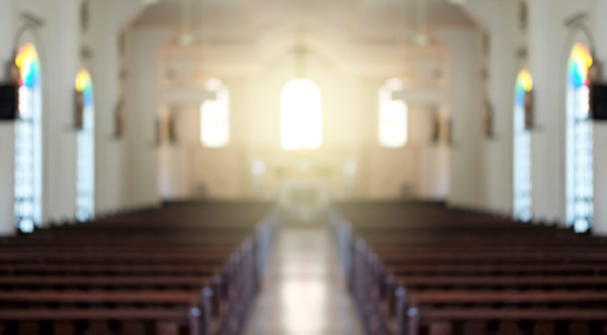 Photo of a church sanctuary showing rows of empty pews
