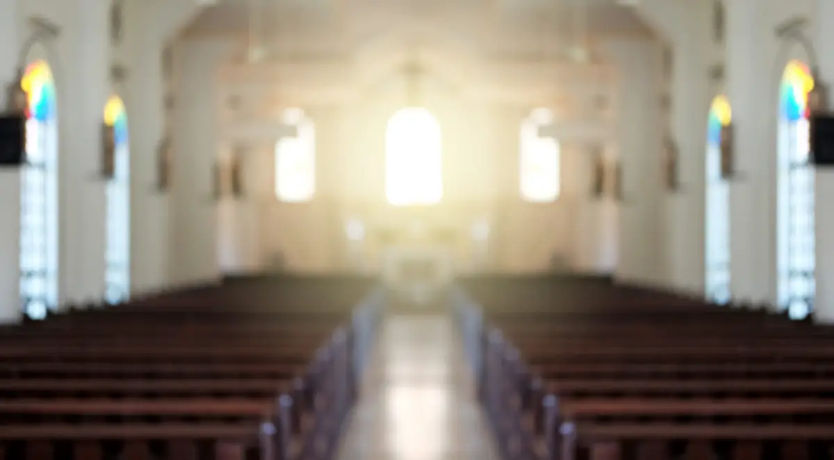 Photo of a church sanctuary showing rows of empty pews