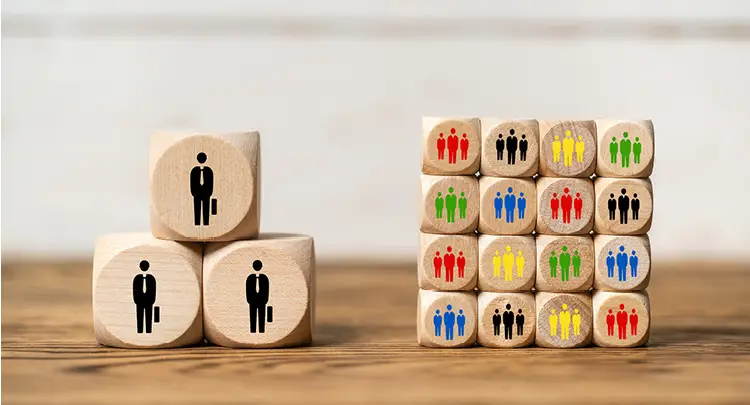 Photo of three large wooden blocks next to a stack of 16 smaller wooden blocks, representing the concept of a wealth gap.