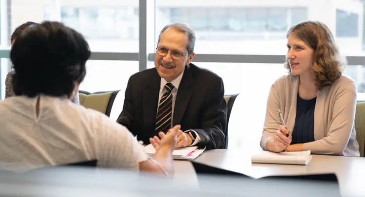 Photo of Juan Olivarez sitting at a conference table with other Johnson Center staff