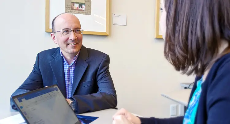 Photo of Jeff Williams sitting at a table and talking with Tory Martin