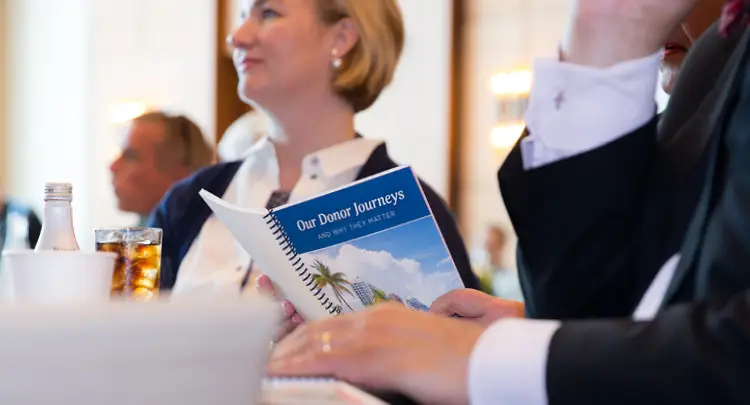 Photo of an attendee reading the program from the 2019 National Summit on Family Philanthropy: Our Donor Journeys and Why They Matter.