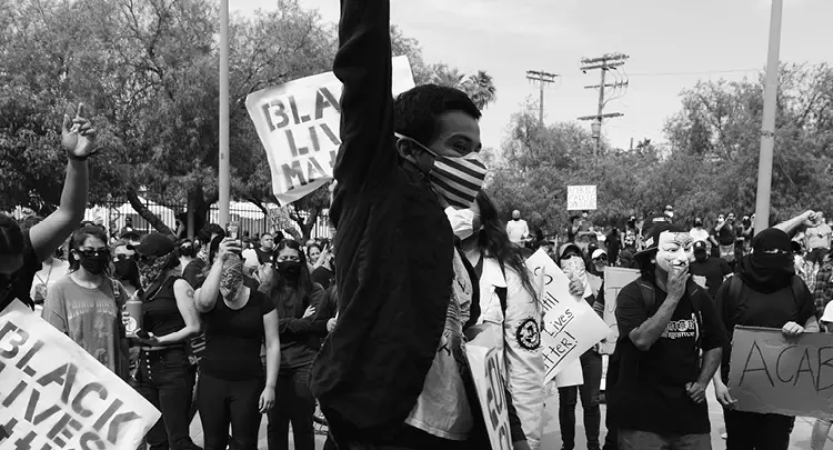 Black & white photo of one of the many "Black Lives Matter" protests, showing a crowd of people wearing face masks and holding signs