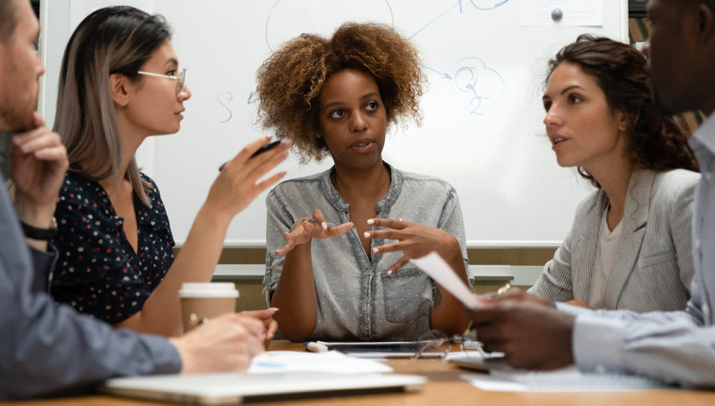 Photo of a group of diverse young professionals talking at a conference table