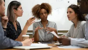 Photo of a group of diverse young professionals talking at a conference table