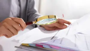Photo of a businesswoman analyzing financial data with a magnifying glass