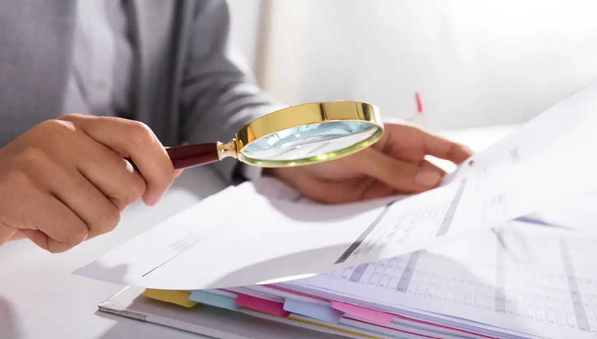 Photo of a businesswoman analyzing financial data with a magnifying glass
