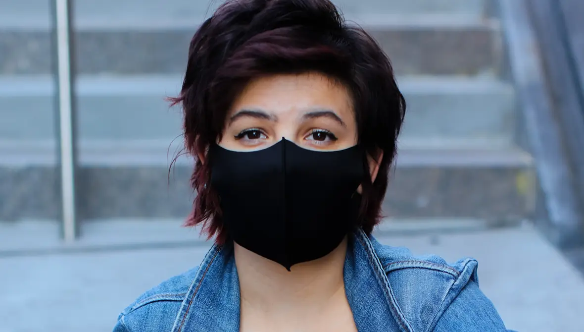 Close-up photo of a woman's face wearing a black mask to help prevent the spread of COVID-19