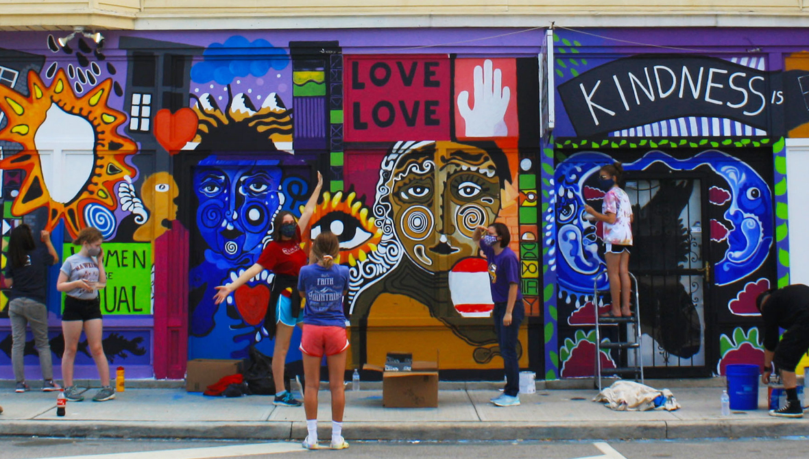 A group of residents paints a colorful mural on the side of a building in Cleveland, Ohio.