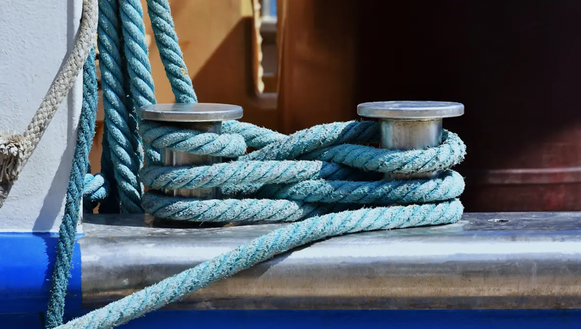 Photo of light blue sailing ropes securely coiled around metal posts