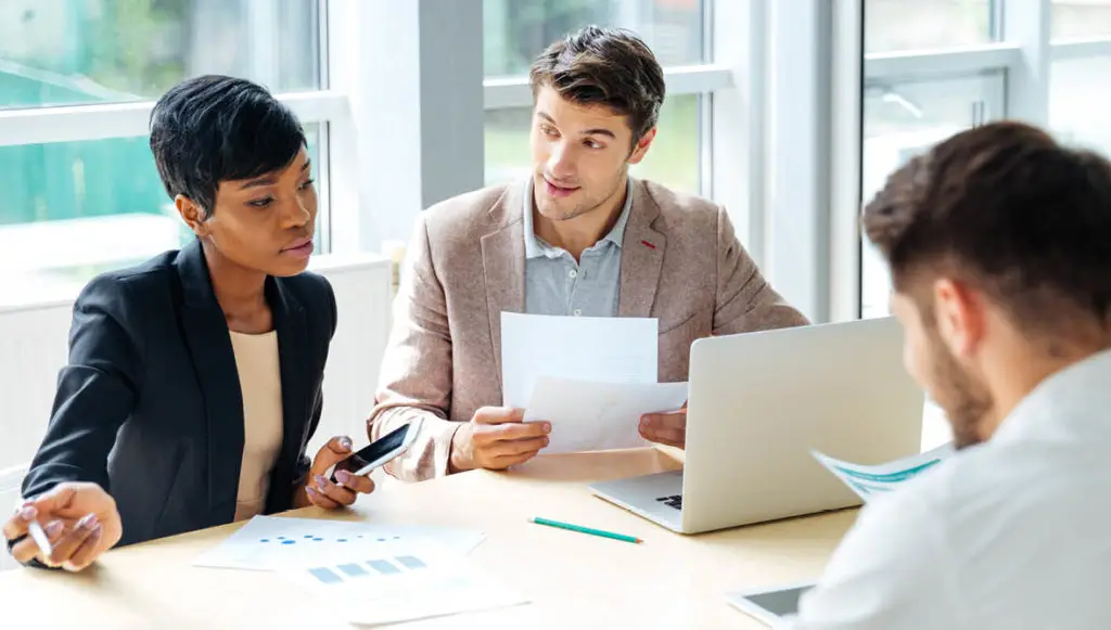 Photo of three professionals sitting at a table having a meeting