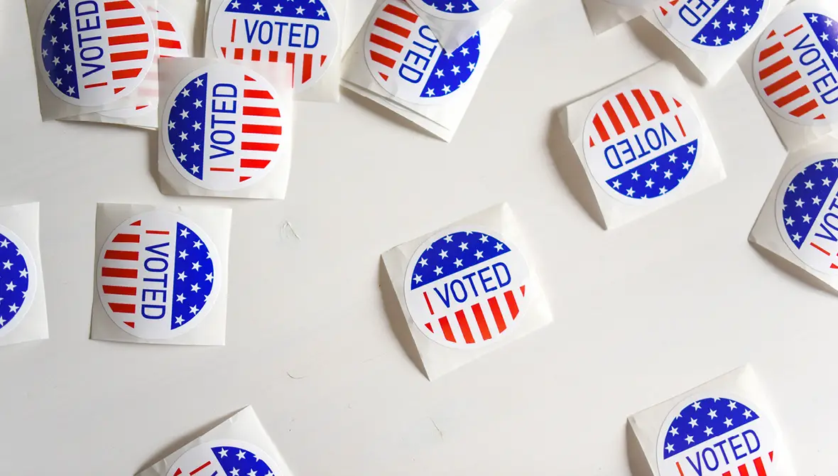Photo of a pile of red, white, and blue "I voted!" stickers scattered on a table