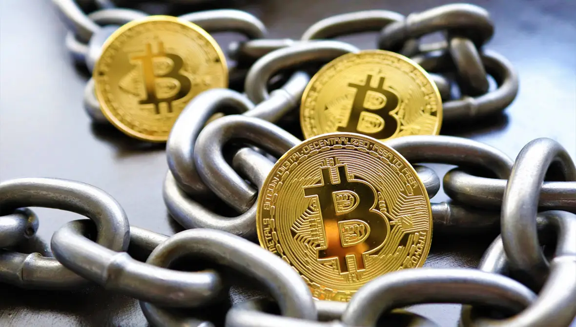 Photo of bitcoins scattered among a strand of chain links, representing cryptocurrency, blockchain, and DAOs