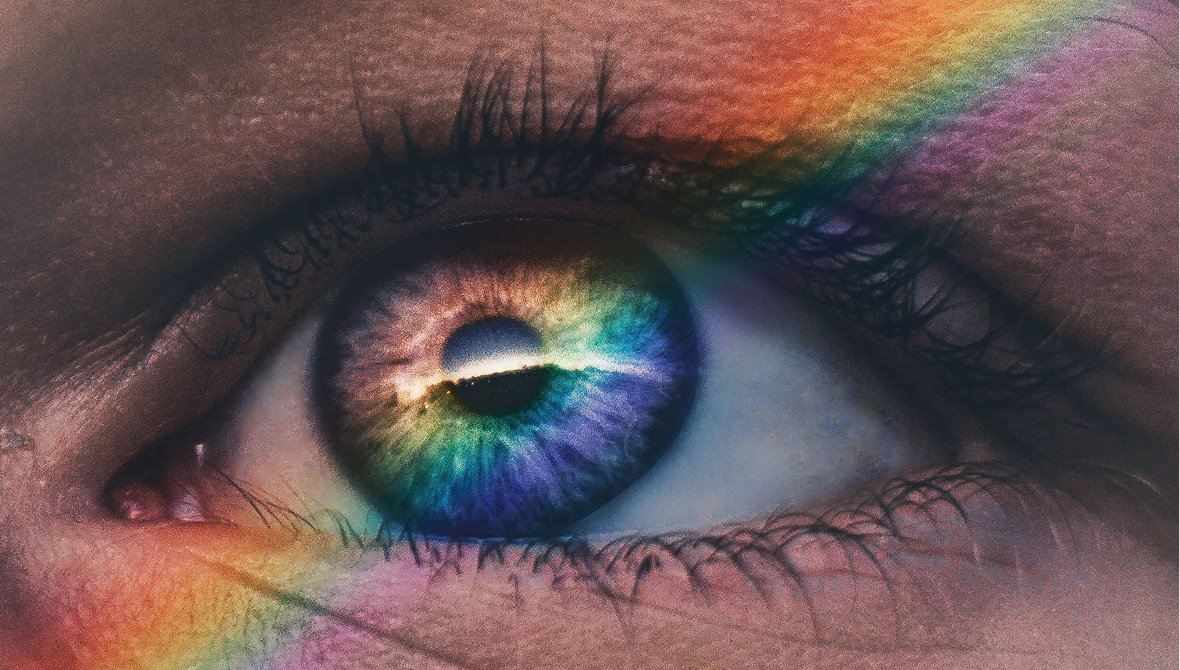 Close-up photo of a human eye with a rainbow of light cast over their face (symbolizing the diverse reality of philanthropy)