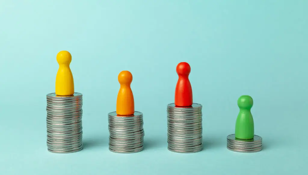 A photo showing four wooden game pieces sitting atop four small stacks of coins, representing the concept of key distinctions or differences