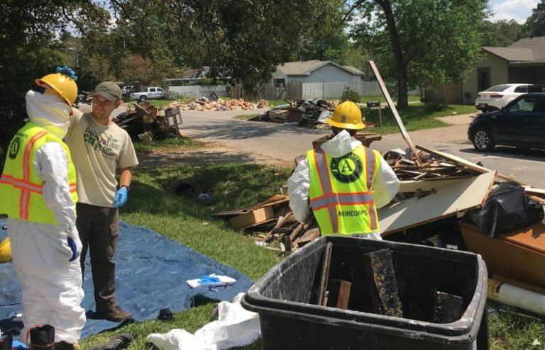 Photo of three Conservation Corps workers cleaning up a neighborhood after a natural disaster.