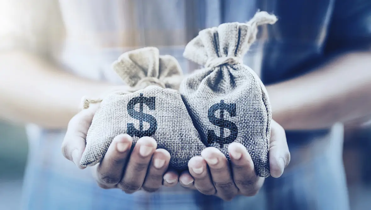 Close-up photo of hands holding two small burlap money bags