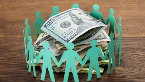 Photo of green paper doll cut-outs propped in a circle around a stack of one hundred dollar bills, representing the concept of collaborative funding