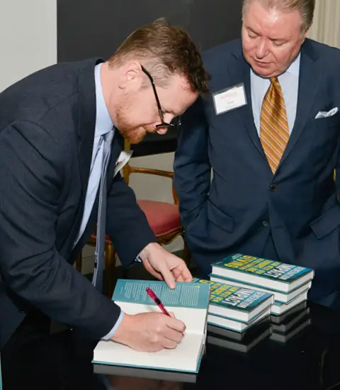 Michael Moody signs a copy of "Generation Impact" for a gentleman standing next to him.