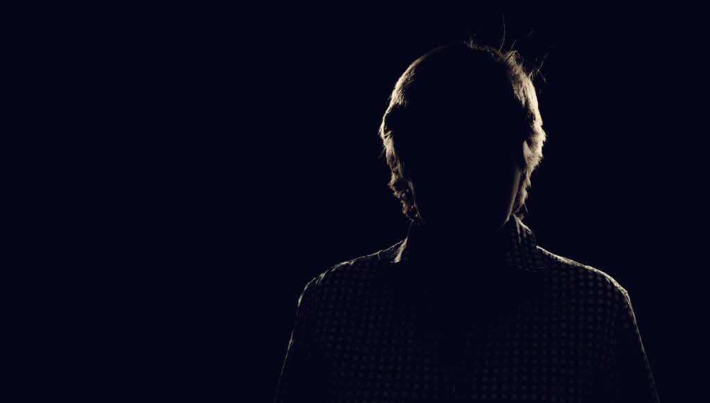 A dark, back-lit silhouette of a man, representing an anonymous donor