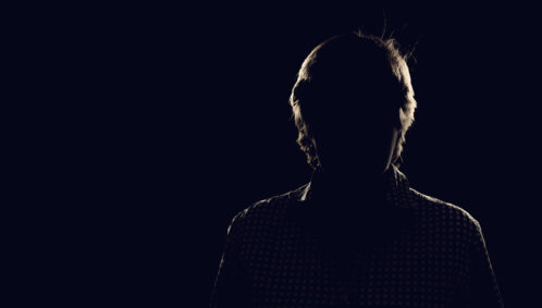 A dark, back-lit silhouette of a man, representing an anonymous donor
