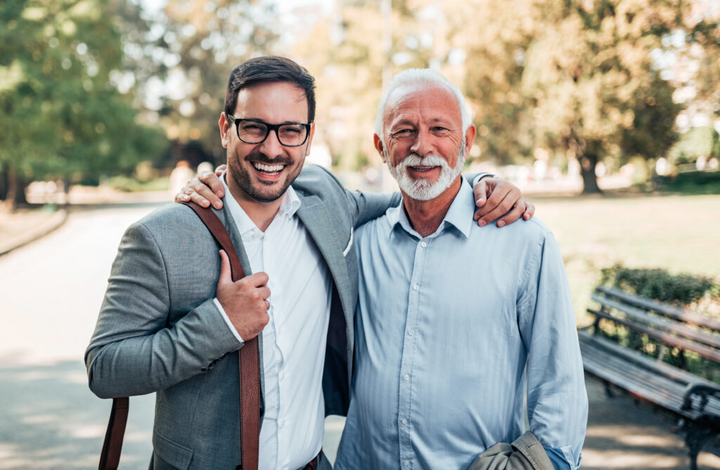 Portrait of a smiling father and his adult son in the park.